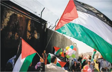  ?? Abbas Momani / AFP / Getty Images ?? Protesters wave Palestinia­n flags at the separation wall near the West Bank village of Bilin on Friday.