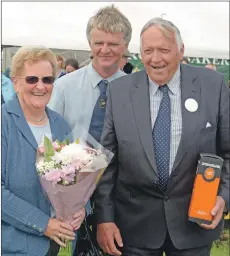  ??  ?? Kintyre Agricultur­al Society president John McLachlan presents Kate McKerral with a bouquet of flowers and Donnie McKerral, who presented the show prizes, with a bottle of whisky.