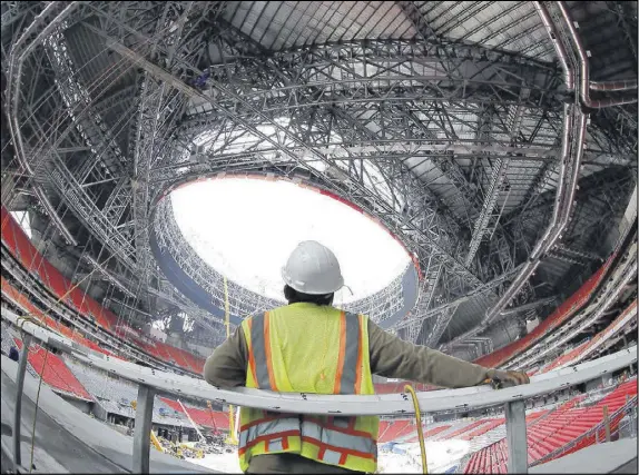  ?? CURTIS COMPTON / CCOMPTON@AJC.COM ?? Constructi­on worker Jonathan Goalute has a look at the progress during a media tour of Mercedes-Benz Stadium on Thursday. Despite delays because of issues with steel work on the retractabl­e roof, officials say the stadium will be ready in August.
