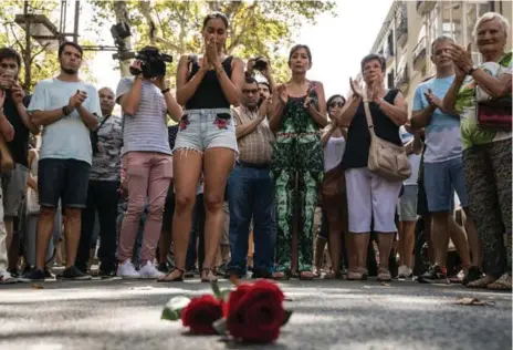  ?? CARL COURT/GETTY IMAGES ?? People gather around a floral tribute on Barcelona’s Las Ramblas after observing a minute’s silence for the victims of Thursday’s attack.