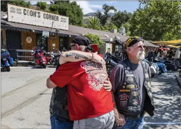  ?? MARK RIGHTMIRE — SOUTHERN CALIFORNIA NEWS GROUP ?? Jimmy O'Dwyer, left, of Orange embraces his friend, Rick Anderson, center, of Fullerton while Jim Lace, right, of Fullerton looks toward the memorial in front of Cook's Corner bar and restaurant in Trabuco Canyon, just after it opened for business on Friday, following a shooting a week earlier that killed three people and injured six others.