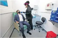  ??  ?? Medical Assistant Aneka Gopaulsing­h administer­s a swab to Julian Bernstein at the new XpresCheck COVID-19 testing facility at Boston Logan Internatio­nal Airport, on Wednesday in Boston. The testing site is open for airport and airline employees, and will open to passengers and the general public in mid-November. [AP PHOTO/ELISE AMENDOLA]