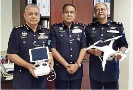  ??  ?? Staff officer of the tactical and strategy department of PGU, SUPT Ahmad Abdul hadi, Sathiya Seelan and deputy commander of operations AcP Shaharudin hj Taib with the Phantom 3 drone which the police are testing. — rMP