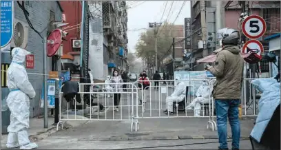  ?? ?? Security guards in personal protective equipments (PPE) are seen at a residentia­l compound under lockdown due to COVID-19 coronaviru­s restrictio­ns in Beijing on Thursday.