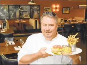  ?? BARBARA HADDOCK TAYLOR/BALTIMORE SUN PHOTOS ?? Master Chef Robert Wiedmaier holds the crabcake sandwich at Keystone Korner, a jazz bar and restaurant in Harbor East.