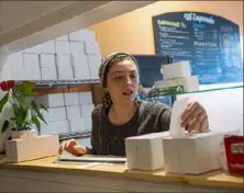  ?? Emily Matthews/Post-Gazette ?? Ciara Teliski, an employee at Mi Empanada, checks a receipt for a takeout order at the Lawrencevi­lle restaurant.