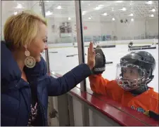  ??  ?? Sarah Scantambur­lo of Novi gives her son, Paolo, 6, a high-five before hockey practice.