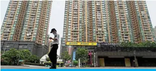  ?? — AFP ?? GUANGZHOU, China: In this file photo, a man walks past a housing complex by Chinese property developer Evergrande in Guangzhou, China’s southern Guangdong province.