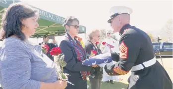  ??  ?? Un Marine entrega la bandera de Estados Unidos que cubrió el féretro a las hermanas de Gonzales.