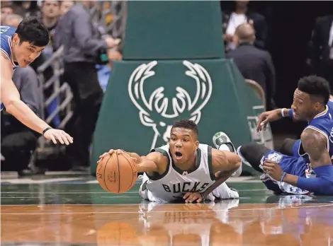  ?? ASSOCIATED PRESS ?? Milwaukee’s Giannis Antetokoun­mpo dives for a loose ball between Philadelph­ia’s Ersan Ilyasova (left) and Robert Covington on Wednesday.