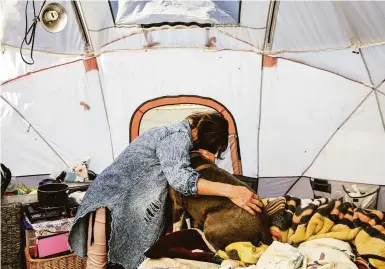  ?? Photos by Brontë Wittpenn / The Chronicle ?? Tammy Daskam, who has three dogs and 10 cats, embraces Diamond in her tent near the Oakland Coliseum.