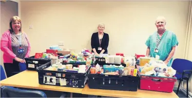  ??  ?? Giving back From left, medical secretary Jane Aitken, medical secretary Lorna Robertson and support worker John Coyle with the food bank donations