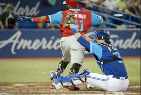  ??  ?? Toronto Blue Jays catcher Danny Jansen, right, tags out Phillies baserunner Carlos Santana at home plate during the fifth inning Saturday in Toronto.
