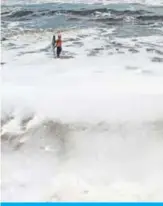  ??  ?? CHENNAI: (Left) A fisherman retrieves fish from his net as foamy discharge, caused by pollutants, mixes with surf on a beach yesterday. (Right) A youth plays in the foamy discharge. — AFP