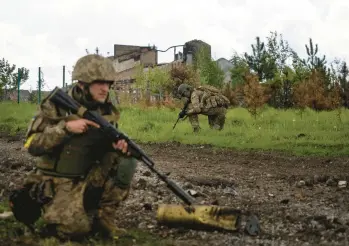  ?? MSTYSLAV CHERNOV/AP ?? Ukrainian servicemen on patrol Sunday in a village north of Kharkiv that was recently retaken.