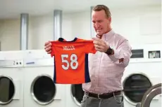 ?? DENVER BRONCOS VIA AP ?? During filming for the Denver Broncos’ 2021 schedule release video, former quarterbac­k and current ‘intern’ Peyton Manning washes a Von Miller jersey at UCHealth Training Center in Englewood, Colo.