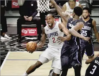  ?? Gina Ferazzi Los Angeles Times ?? KAWHI LEONARD scores on a reverse layup behind Orlando Magic center Mo Bamba during the second half Tuesday. Leonard finished with 28 points and five rebounds in the Clippers’ 103-96 loss.