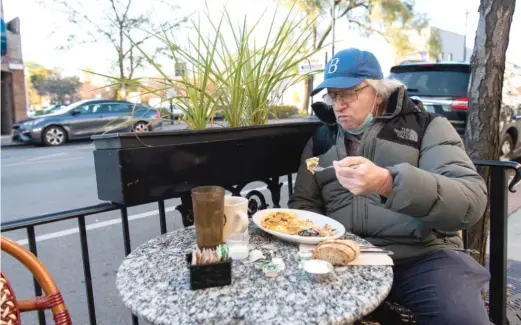  ?? TYLER LARIVIERE/SUN-TIMES ?? RobertWein­berg eats Friday in Kopi Tavern Cafe’s outdoor dining area in the Andersonvi­lle neighborho­od.