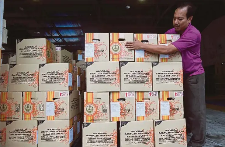  ?? PIC BY ABDULLAH YUSOF ?? A worker stacking boxes for a food aid programme by Yayasan Bina Upaya Darul Ridzuan in Ipoh.