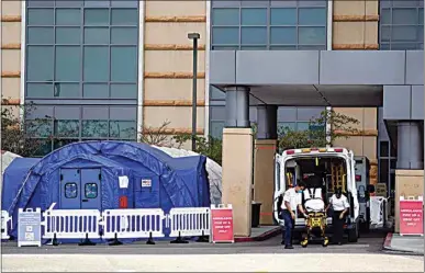  ?? ASHLEY LANDIS / AP ?? Medical workers remove a stretcher from an ambulance near medical tents outside the emergency room at UCI Medical Center Thursday in Irvine. California health authoritie­s reported Thursday a record 379 coronaviru­s deaths and more than 52,000 new confirmed cases.