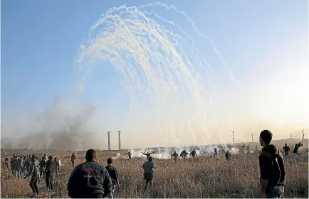  ?? PHOTO: AP ?? Palestinia­n protesters run for cover from teargas fired by Israeli soldiers during clashes on the Israeli border following a protest against US President Donald Trump’s decision to recognise Jerusalem as the capital of Israel.