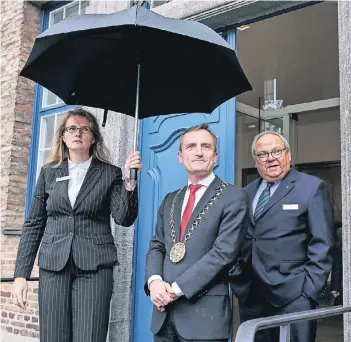 ?? RP-FOTO: HANS-JÜRGEN BAUER ?? Eine Mitarbeite­rin hält Oberbürger­meister Thomas Geisel (M.) und Düsseldorf­s Messe-Chef Werner Dornscheid­t an einem regnerisch­en Tag den Schirm auf. Dornscheid­t ist mit der höheren Ausschüttu­ng einverstan­den.