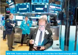  ?? — AFP ?? NEW YORK: Traders works after the opening bell at the New York Stock Exchange (NYSE) on Wall Street, on Friday.