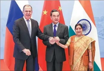  ?? ZOU HONG / CHINA DAILY ?? State Councilor and Foreign Minister Wang Yi (center) clasps hands with his Russian counterpar­t Sergei Lavrov (left) and Indian counterpar­t Sushma Swaraj for a group photo before their trilateral meeting in Wuzhen, Zhejiang province, on Wednesday.