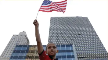  ?? (Reuters) ?? A YOUNG boy holds an American flag in front of the Federal Office Building in New York City.