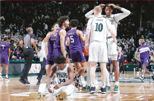  ?? AL GOLDIS/AP ?? Northweste­rn players (in purple) celebrate their upset victory Saturday against No. 10 Michigan State, which saw its nine-game winning streak snapped.