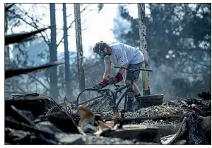  ?? Bloomberg file photo ?? A resident searches the rubble after a wildfire destroyed his home in Napa, Calif., last October. The Pacific Gas &amp; Electric Co. power lines are being blamed for sparking some of last fall’s blazes in the state.