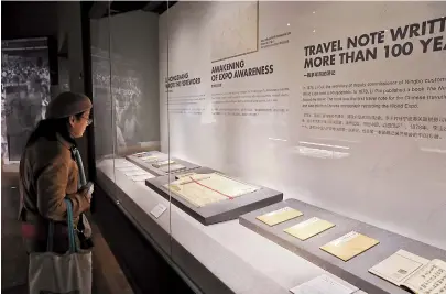  ??  ?? A visitor examines documents related to the history of the World Expo. — Jiang Xiaowei