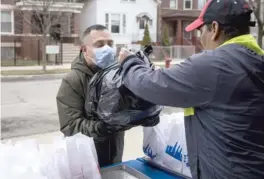  ??  ?? Jaime Funes, father of two students at Nixon Elementary, receives his family’s meals.