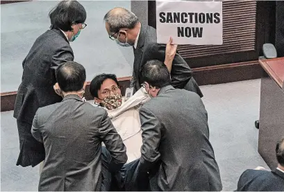  ?? ANTHONY KWAN GETTY IMAGES ?? Pro-democracy lawmaker Eddie Chu is removed by security during a scuffle with pro-Beijing lawmakers in Hong Kong Friday.