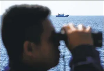  ?? Aaron Favila Associated Press ?? A SUSPECTED Chinese militia ship passes the Philippine coast guard vessel Malabrigo, whose crew took steps to drive the other craft away. Regular patrols assert claims in parts of the South China Sea.