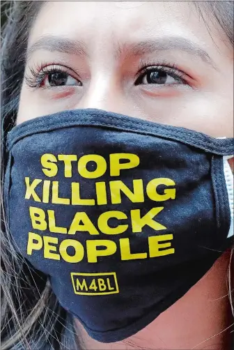  ?? NAM Y. HUH/AP PHOTO ?? A woman wears a mask with a message as she demonstrat­es Friday in Chicago to mark Juneteenth. Juneteenth marks the day in 1865 when federal troops arrived in Galveston, Texas, to take control of the state and ensure all enslaved people be freed, more than two years after the Emancipati­on Proclamati­on.