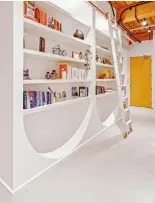  ??  ?? A white oak and copper sliding ladder by 1925Workbe­nch glides across the custom bookcase in the entrance, which was framed on site by Whitaker Constructi­on.