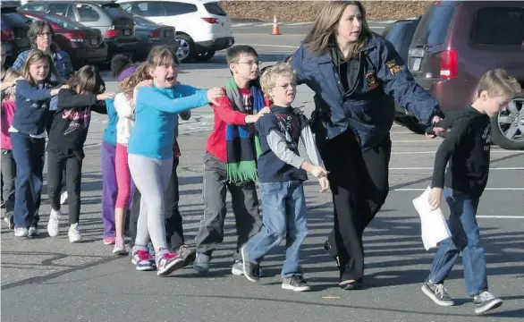  ?? THE ASSOCIATED PRESS/ NEWTOWN BEE, SHANNON HICKS ?? Connecticu­t State Police escort children from the Sandy Hook Elementary School in Newtown, Conn., on Friday after a mass shooting.