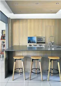  ??  ?? The kitchen is open to the dining area. The wood and metal stools are by Pedersen & Lennard.