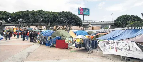  ??  ?? SACRIFICIO. Los migrantes que esperan ser atendidos acampan para no perder su lugar en la fila.