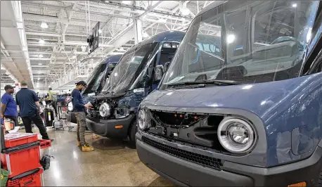  ?? RON JOHNSON FOR THE ATLANTA JOURNAL-CONSTITUTI­ON BY RON JOHNSON ?? Manufactur­ing workers assemble electric vehicles including the Rivian Amazon EDV 700 at the Rivian factory in Normal, Ill., in July. Rivian electrifie­d Georgia economic news in December by announcing a $5 billion factory along I-20.