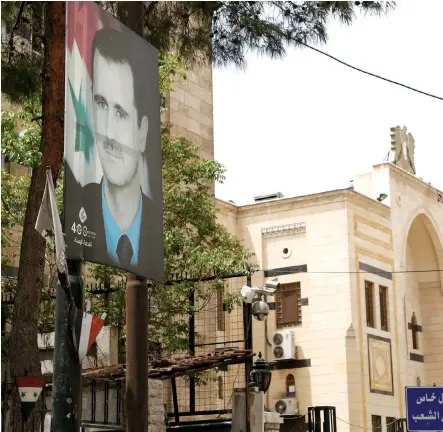  ?? (Yamam al Shaar/Reuters) ?? A PICTURE of Syria’s President Bashar Assad hangs outside the parliament building in Damascus in April.