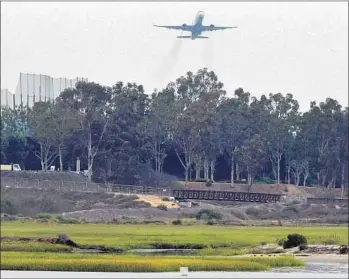  ?? Don Bartletti Los Angeles Times ?? A PLANE flies over Newport Beach after leaving John Wayne Airport in 2013. A report says inefficien­t air control tower operations nationwide added $853 million to the FAA’s costs from 2008 to 2013.
