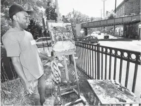  ??  ?? Stanley Agbontaen uses a palette knife to achieve a textured effect on his view of the railroad trestle and traffic at the end of Main Street.