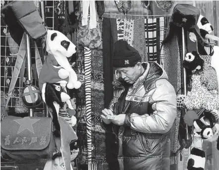  ??  ?? A shopper pays for a hat at a store in a shopping street in Beijing. Services that cater to a growing middle class offer an opportunit­y to cash in on a shift in consumptio­n patterns as Chinese consumers move increasing­ly up the value chain. — AFP