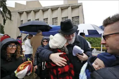  ?? GENE J. PUSKAR — THE ASSOCIATED PRESS ?? Rabbi Chuck Diamond, center, a former Rabbi at the Tree of Life Synagogue, hugs a woman Saturday after leading a Shabbat service outside the synagogue in Pittsburgh.