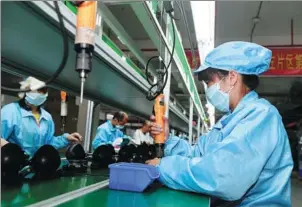  ?? LU BOAN / XINHUA ?? Workers operate on a production line for export-bound electronic devices at a factory in Pingxiang, Guangxi Zhuang autonomous region.