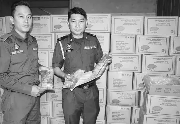  ??  ?? Salihin (right) and his enforcemen­t officer showing the 1kg cooking oil packets stored in the warehouse ready for distributi­on.