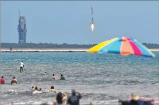  ??  ?? Crowds watch the landing from on the beach and in the ocean in Cape Canaveral, Fla., of the Spacex Falcon 9 at Kennedy Space Center Monday.