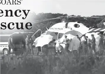  ?? AGENCE FRANCE PRESSE ?? Police and military personnel use umbrellas to cover around a stretcher near a helicopter and an ambulance at a military airport in Chiang Rai, as rescue operations continue for those still trapped inside the cave in Khun Nam Nang Non Forest Park in...